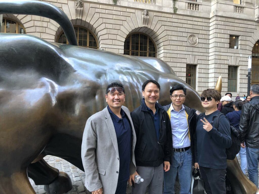 a group photo of the founders behind the Charging Bull sculpture.