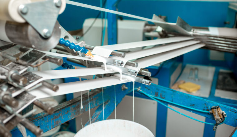 Automated machinery applying packaging glue on conveyor belt with precision.